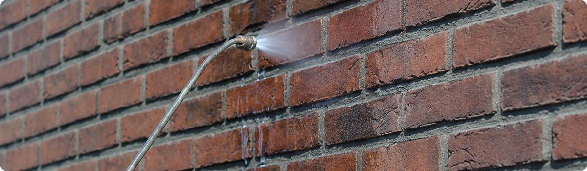 Applying facade impregnation with a spray lance on a brick wall